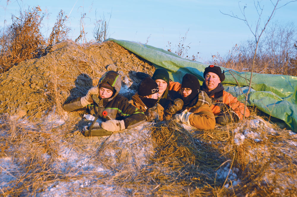 Mike McKay and some of his students are crouched in a trench for their annual Night in the Trenches to honour war veterans.