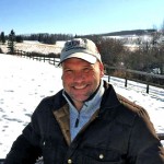 Man standing in an open field with snow on the ground.