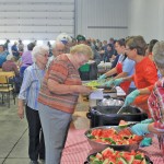 Vauxhall & District Growing Project’s annual pig roast draws a big crowd, but there’s room for everyone in the loading area of Bennen Farms’ potato storage warehouse. Photo: Canadian Foodgrains Bank