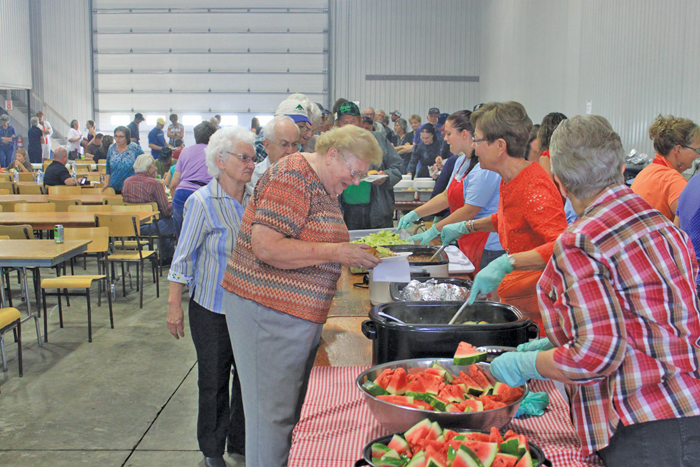 Vauxhall & District Growing Project’s annual pig roast draws a big crowd, but there’s room for everyone in the loading area of Bennen Farms’ potato storage warehouse.  Photo: Canadian Foodgrains Bank