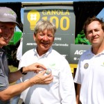 The game is on…If you think you can do a pretty good job of growing canola, the Agri-Prize Challenge announced at this week’s Ag In Motion farm show near Saskatoon is right up your alley. Farmers across Canada and northern U.S. states are being urged to register for the challenge to see who can be the first to produce a 100 bushel/acre canola crop over the next three years. Aside from the bragging rights there is a pretty decent prize that goes with the challenge. The first person to produce 100 bushels of canola on 50 acres, or the person with the highest yield after the three-year term of the contest will win the use of a whole fleet of John Deere equipment for 100 hours of field work — that includes a tractor, air seeding system, field sprayer, swather and combine. Above are representatives of contest sponsors, from left, Jon Kennedy, president of Glacier Media, he’s pinning a 100 bushel contest pin on Rob Saik, president of Agri-Trend Agrology, while Glen Walsh, with John Deere looks on. For more information visit the contest website at: www.agriprize.com.