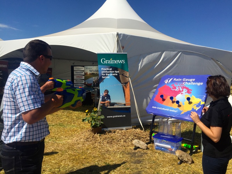Two Saskatchewan farmers take up the rain gauge challenge with water pistols at the CocoRaHs water gun booth.
