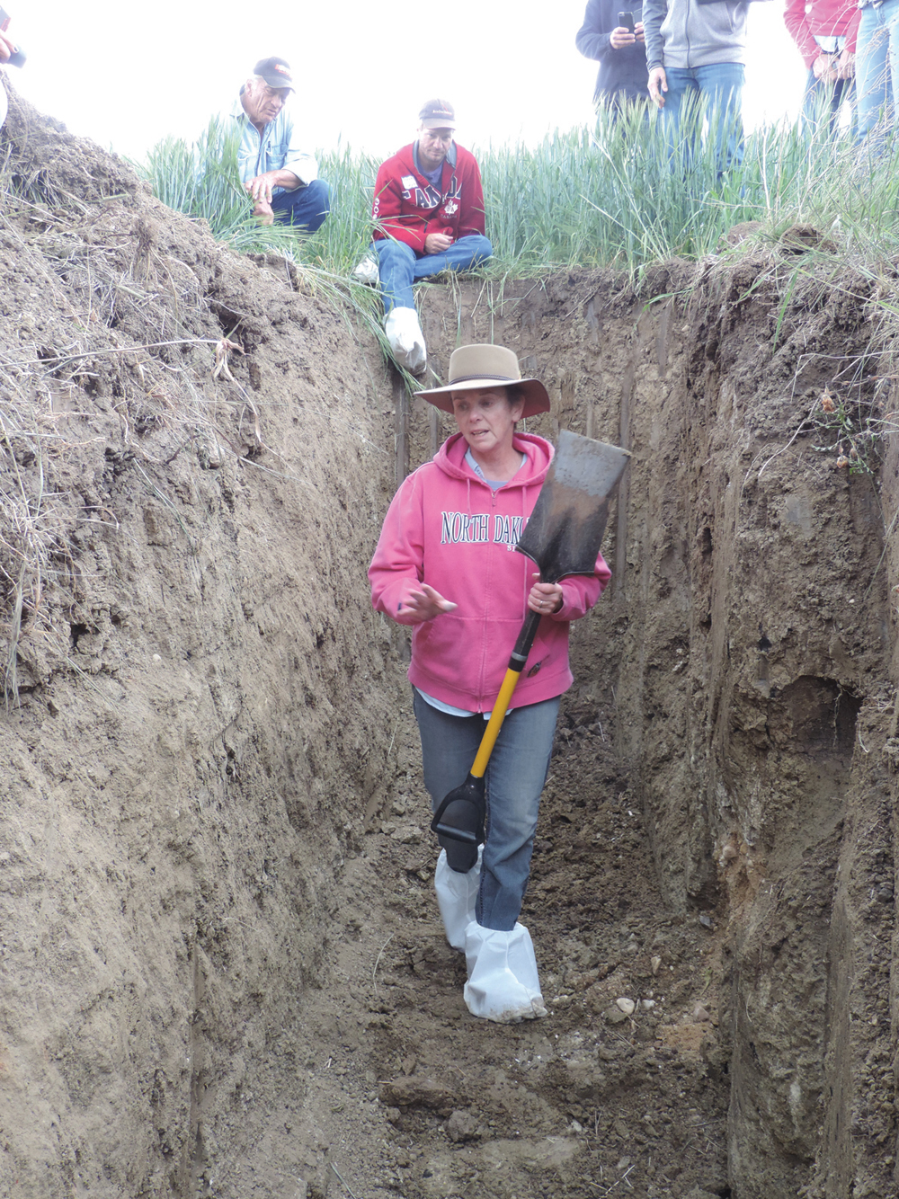Renowned soil scientist Jill Clapperton climbs into a pit to show some features of soil, during a hands-on workshop on soil health.