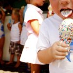 Boy (3-5) eating ice cream, close-up, other children in background