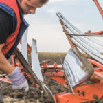 Young mechanic fixing plow on the tractor