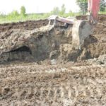 A backhoe digs manure out from around a 2009 Steiger 485. Photo courtesy Fisher Branch RCMP.
