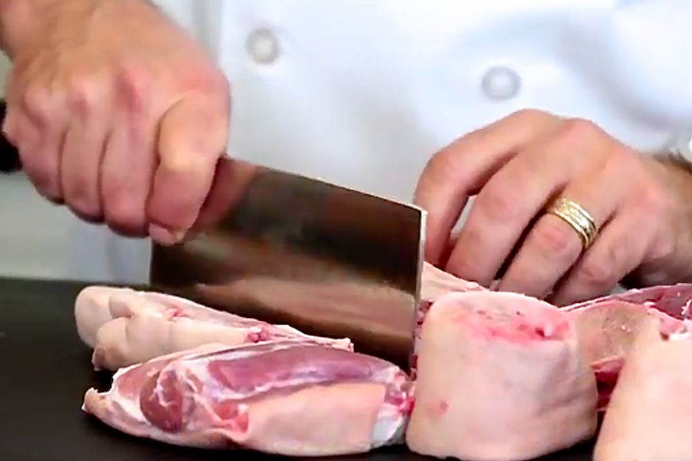 Chef Jonathan Collins cuts up a pork leg, foot included, to prepare ginger and black vinegar hog trotters in a video for Canada Pork International. (Video screengrab from CanadaPork.com)
