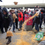 Farmers dump bags of corn grain in front of the Papineau riding office of Prime Minister Justin Trudeau in Montreal, as they protest the lack of propane due to the CN strike, on Nov. 25, 2019.