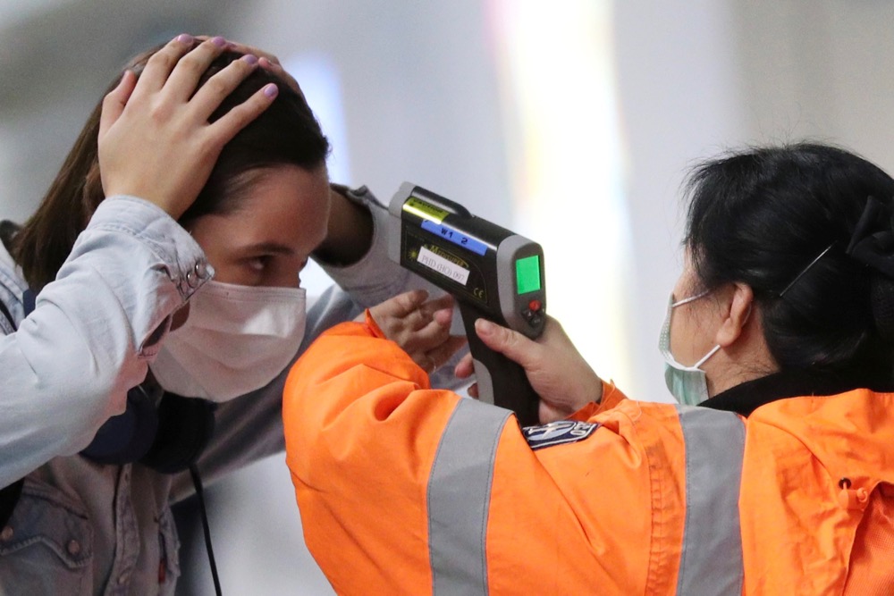 A worker checks the temperature of a passenger arriving into Hong Kong International Airport with an infrared thermometer on Feb. 7, 2020. (Photo: Reuters/Hannah McKay)
