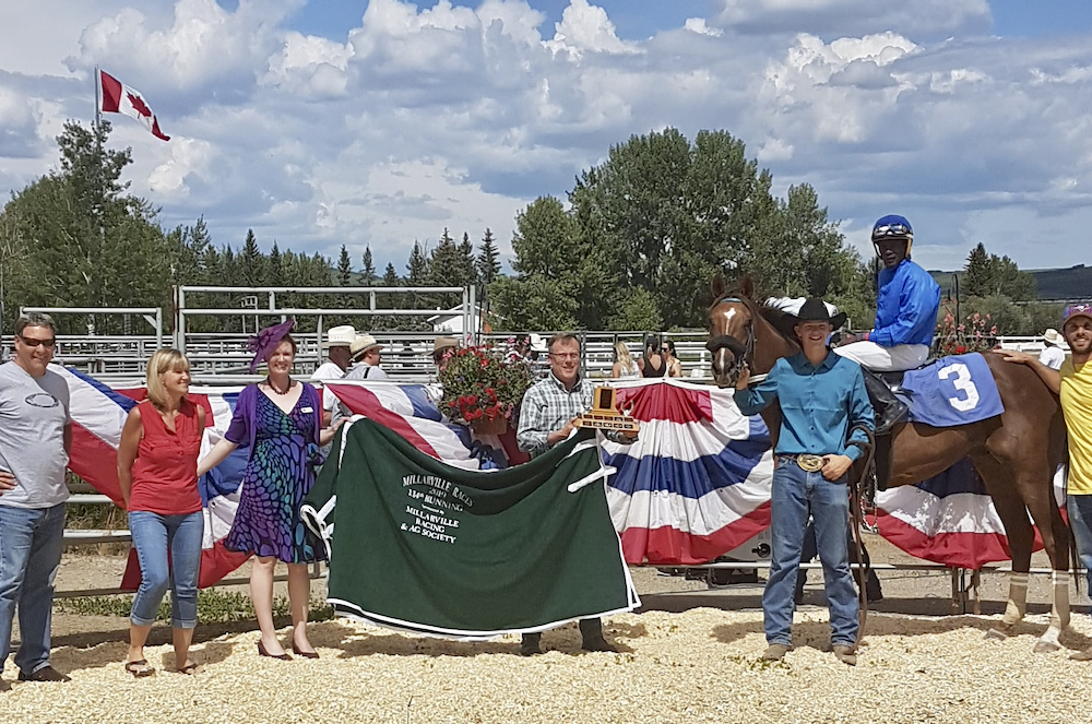 A lot has changed in the last two years but along with the challenges has come innovation and a surge of volunteer spirit, says Anna De Paoli, pictured here (dressed to the nines) with race event chair Brent Foster presenting a blanket to the winner of the 2019 Millarville Derby, one of many events put on by the Millarville Racing and Agricultural Society.