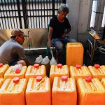 Workers fill jerrycans with cooking oil at a distribution station in Jakarta, Indonesia on May 20, 2022. (Photo: Reuters/Willy Kurniawan)