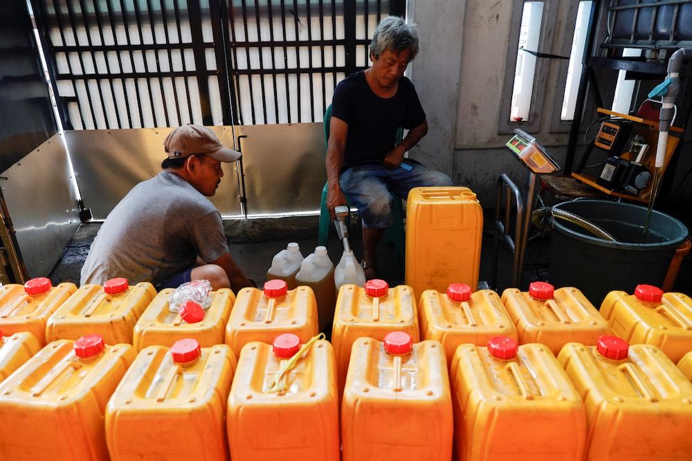 Workers fill jerrycans with cooking oil at a distribution station in Jakarta, Indonesia on May 20, 2022. (Photo: Reuters/Willy Kurniawan)
