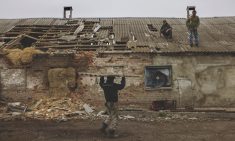 Workers repair the roof of a farm building that was damaged by a mortar in the village of Malaya Rohan, in the Kharkiv region, Ukraine, April 9, 2022.