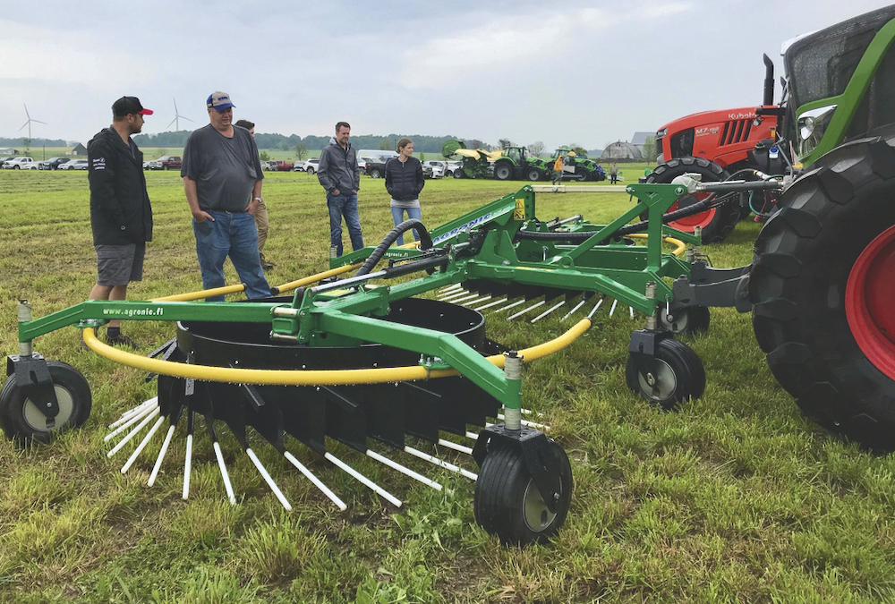 Aric Wilson of Leading Edge Equipment(left) discusses the Finnish-made, front-mounted Agronic rake during the Ontario Forage Expo.