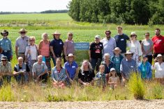 Attendees at the launch event pose next to the Treaty Land Sharing Network sign at Brenda Bohmer's farm near Bawlf.