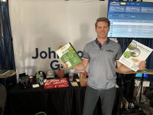Joel Merkosky, president of Johnston’s Grain, shows off some of the firm’s brochures at its booth at the Ag in Motion 2025 show in Langham, Sask.Joel Merkosky, president of Johnston’s Grain, attended Ag in Motion 2025 to explain his company’s move into regenerative agriculture. Photo: Sean Pratt
