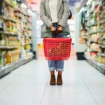 Supermarket aisle, woman legs and basket for shopping in grocery store. Customer, organic grocery shopping and healthy food on groceries sale shelf or eco friendly retail purchase in health shop
