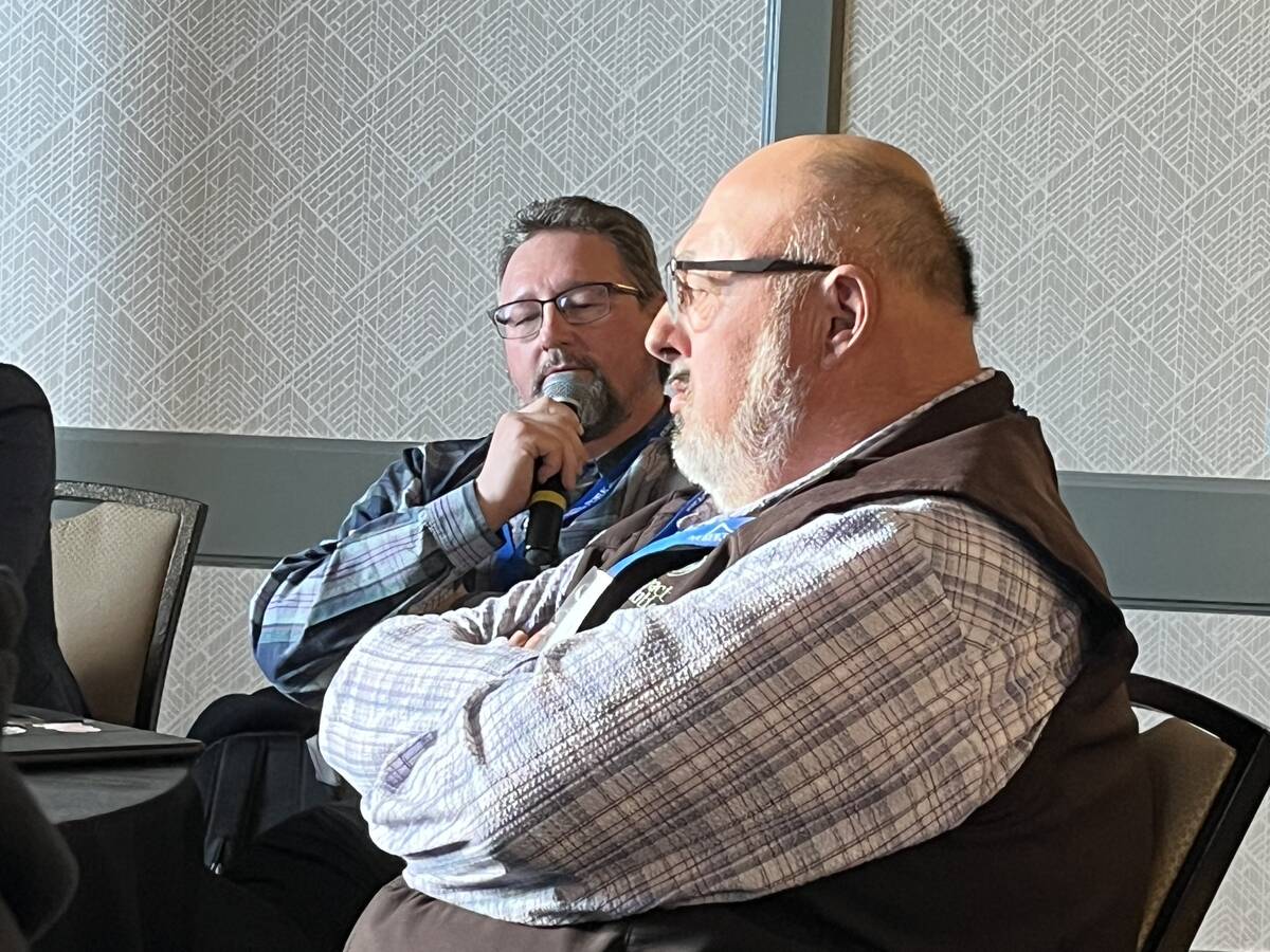 Pork producer Martin Waldner speaks into a microphone at the Alberta Pork meeting in Lethbridge, with a fellow producer seated beside him. Photo: Greg Price.