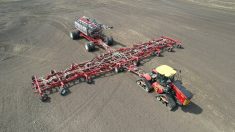 Aerial view of the Morris Quantum 100-foot air seeder fully extended in a bare field, paired with a Morris 10 Series 1440-bushel air cart and a red tracked tractor. The seeder, aimed at crop producers farming around 9,000 acres, is scheduled for full commercial release in 2027. Photo: Superior Farms Equipment