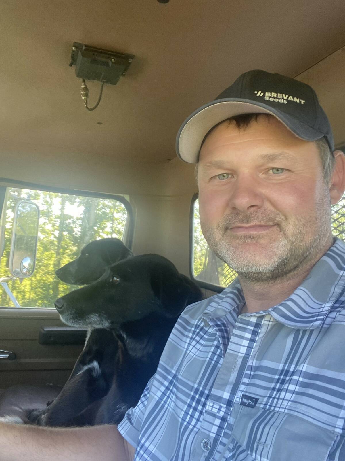 Colby Hansen, a farmer from between Westlock and Athabasca, Alta., sitting in a truck cab with a black dog beside him. Photo: supplied