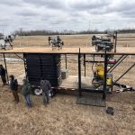 Attendees at the Canadian Agricultural Drone Association conference in Camrose examine a drone tender trailer loaded with agricultural spray drones on display in a field. Photo: Mary MacArthur