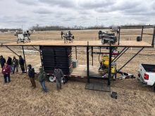 Attendees at the Canadian Agricultural Drone Association conference in Camrose examine a drone tender trailer loaded with agricultural spray drones on display in a field. Photo: Mary MacArthur