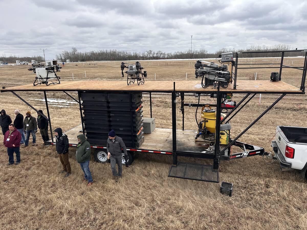 Attendees at the Canadian Agricultural Drone Association conference in Camrose examine a drone tender trailer loaded with agricultural spray drones on display in a field. Photo: Mary MacArthur